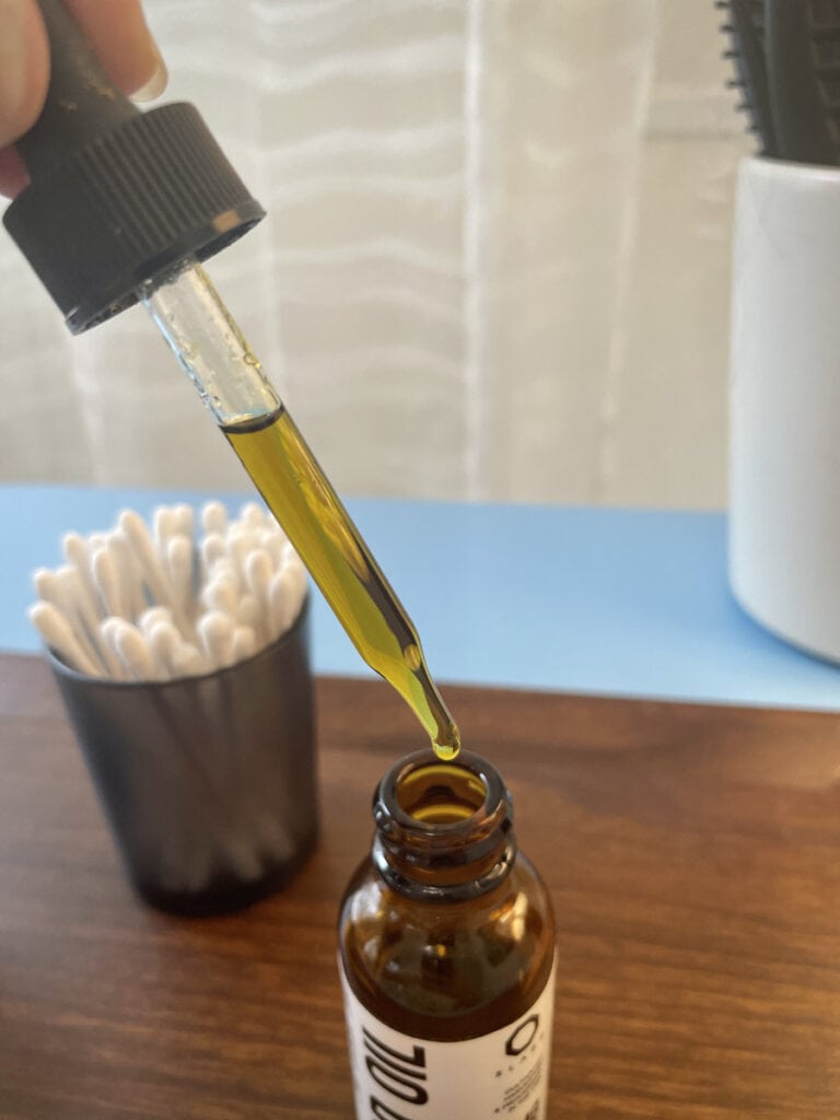A close-up shot of a dropper of CBD oil from 8Labs on a wooden bathroom counter - Annie's CBD Guide